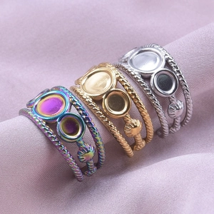 Three-color twisted stainless steel rings with circular trays on purple satin fabric