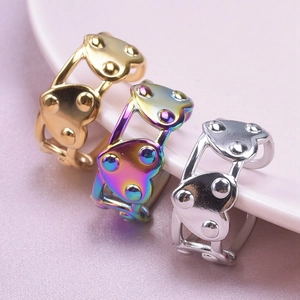 Detail of hollow heart rings in gold, rainbow, and silver on a silk background