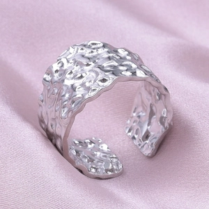 Detailed macro shot of silver 304 stainless steel ring with hammered texture on pink silk
