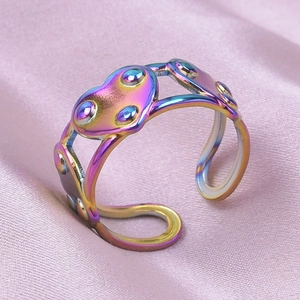 Macro view of rainbow stainless steel adjustable open ring with heart patterns and dot texture