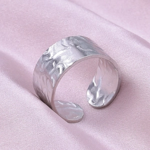 Detailed close-up of adjustable stainless steel ring with a hand-hammered texture on silk