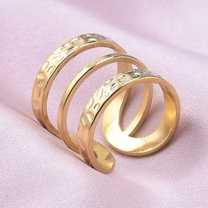 Detail of multi-layer golden ring with hammered and mirror finish on pink satin fabric