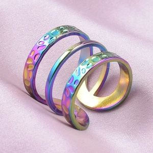 Macro detail of three iridescent 304 stainless steel open rings on purple silk fabric
