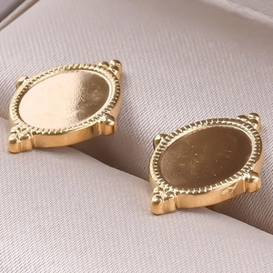 Vue macro de boucles d'oreilles ovales dorées avec bordure grain de riz et style rétro