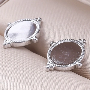 Vue macro de boucles d'oreilles ovales vintage en acier inoxydable avec bords en relief