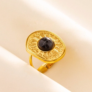 Detailed view of an adjustable gold ring featuring a black stone and sunburst engraving
