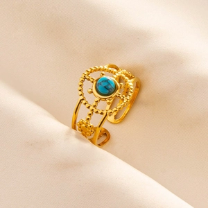 Dettaglio di un anello dorato traforato e regolabile con una pietra preziosa turchese blu