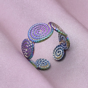 Macro detail of rainbow gradient spiral pattern ring on elegant purple silk fabric