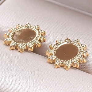 Détail macro de boucles d'oreilles tournesol en acier inoxydable 304 doré sur un écrin