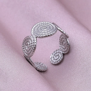 Detailed side view of silver adjustable spiral thread ring on pink satin fabric