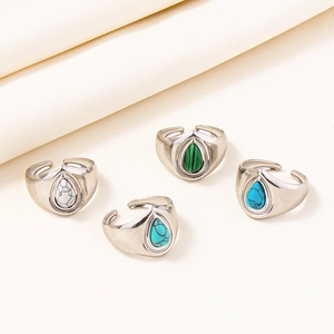 Detail of adjustable silver rings with colorful teardrop stones on cream fabric