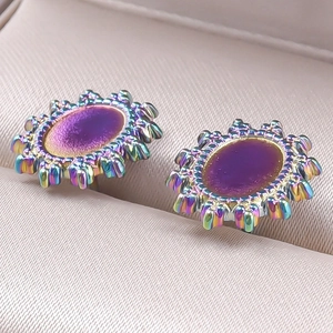 Détail macro de boucles d'oreilles tournesol ovales avec pierre violette et métal arc-en-ciel
