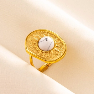 Detailed shot of golden sunburst ring with white turquoise stone on silk fabric