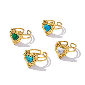 Set of four gold stainless steel heart rings with colorful stone inlays on white background