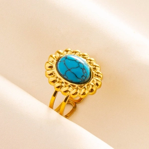 Détail d'une bague dorée ajustable avec pierre ovale bleue et bords de pétales bohèmes