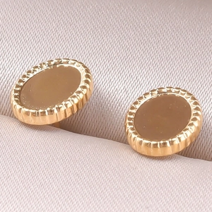 Vue macro des boucles d'oreilles dorées avec bords perlés dans une boîte en soie rose