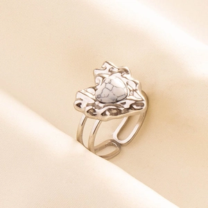 Detail of silver lava style open ring with white heart turquoise stone on beige fabric