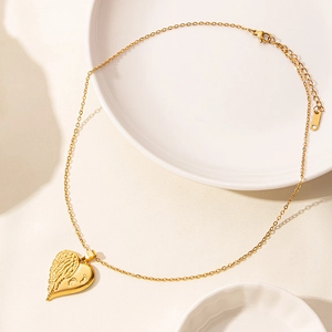 Collana a cuore in oro 18k con ala di piuma e impronta su piatto in ceramica bianca