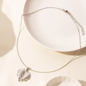 Dettaglio di una collana in acciaio inox argento con pendente a cuore a doppia piuma