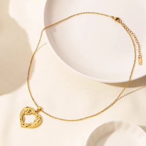 Dettaglio macro della collana con ciondolo a cuore in oro 18K con motivi filigranati cavi