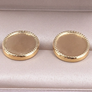 Gros plan d'une base de boucle d'oreille en acier doré sur satin champagne
