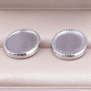 Détail macro de bases de boucles d'oreilles ovales en acier inox avec bordure texturée