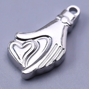 Macro de colgante de manos sosteniendo un corazón en acero 304 para creación de joyería DIY