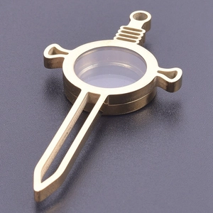 Detalle de un colgante de relicario dorado en forma de espada con ventana de cristal
