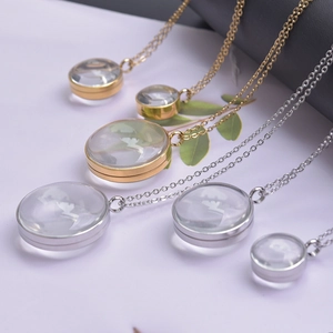 Détail de médaillons ronds en verre en finitions or et argent sur fines chaînes en métal