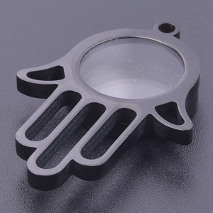 Macro detail of black stainless steel Hamsa Hand locket with transparent glass insert