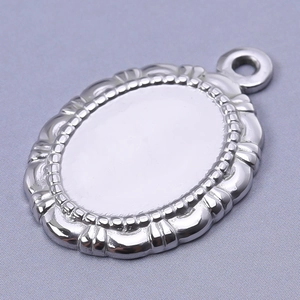 Detalle de un colgante de acero inoxidable plateado con borde floral en relieve y brillo