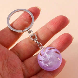 Detail of hand holding a creative purple swirl keychain with silver metal ring and glitter
