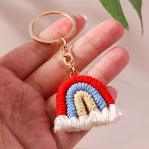 Detail of handmade woven rainbow keychain with three-color cotton cord and white tassels