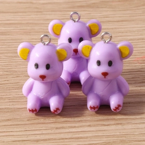 Detailed macro view of three lavender resin bear charms with metal hooks on wooden background