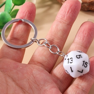 Close-up of a white 20-sided D20 dice keychain with clear black numbers held by hand