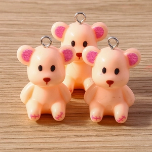 Cute resin bear charms in peach color with metal loop on light wood background