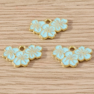 Detailed macro view of three light blue enamel flower charms on rustic wood surface