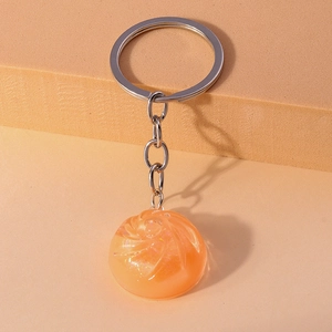 Macro detail of a translucent orange crystal ball keychain with glitter and silver metal ring