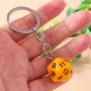 Close-up of hand holding a bright yellow d20 dice keychain with clear black numbers