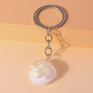 Close-up of pink spiral bun keychain with polished silver ring on orange background