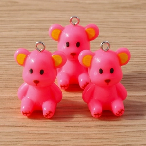 Detailed view of three pink resin bear charms with silver metal rings on wooden table