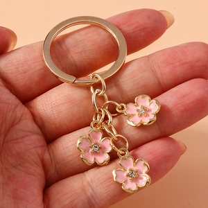 Detail of pink enamel cherry blossom charms with crystal center on golden keychain