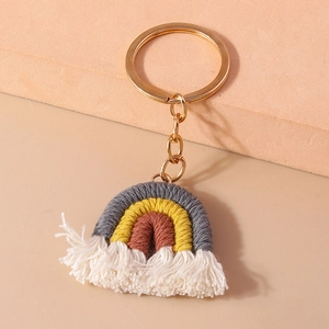Detail of handmade macrame rainbow keychain with white tassels and gold metal clip