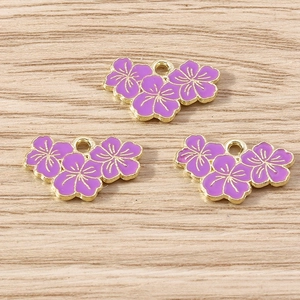 Detail of three purple enamel flower pendants with gold alloy edges for DIY jewelry making