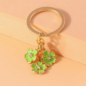 Detail of golden keychain with three green enamel flowers and sparkling crystal center