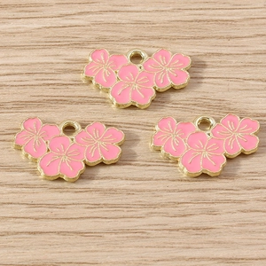 Detailed close-up of pink cherry blossom enamel pendants with gold alloy edges for jewelry DIY