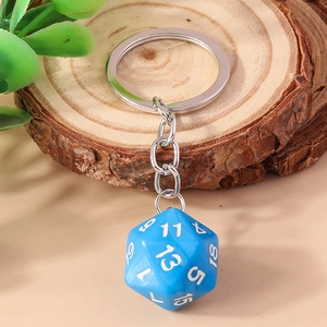 Macro view of blue 20-sided D20 dice keychain on a decorative wooden base