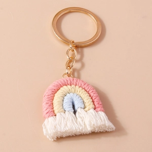 Handmade woven cotton rainbow keychain with tassels and golden ring on pink background