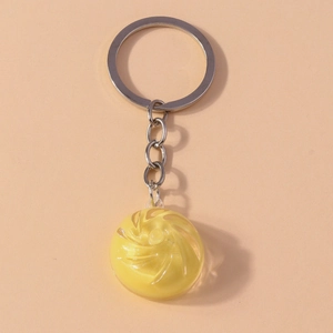 Macro detail of yellow translucent dumpling keychain with spiral texture on pink surface