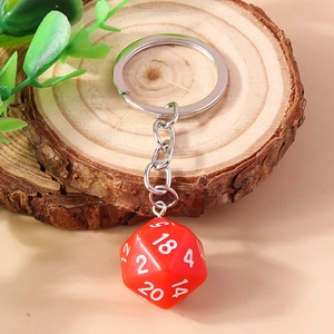 Detail of red 20-sided D20 dice keychain on a wooden display stand with green leaf